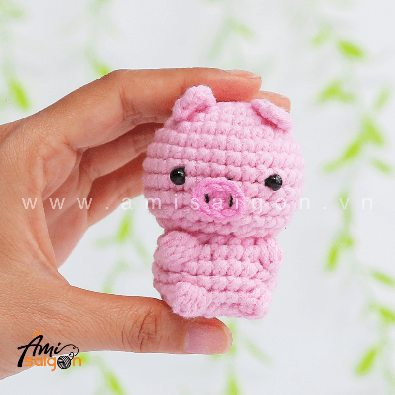 Tiny pink pig amigurumi held in hand